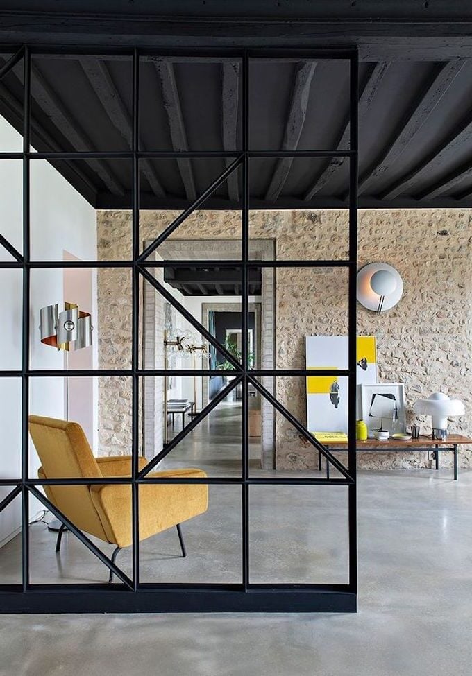 salon estival jaune mur en brique marron verrière métallique noir