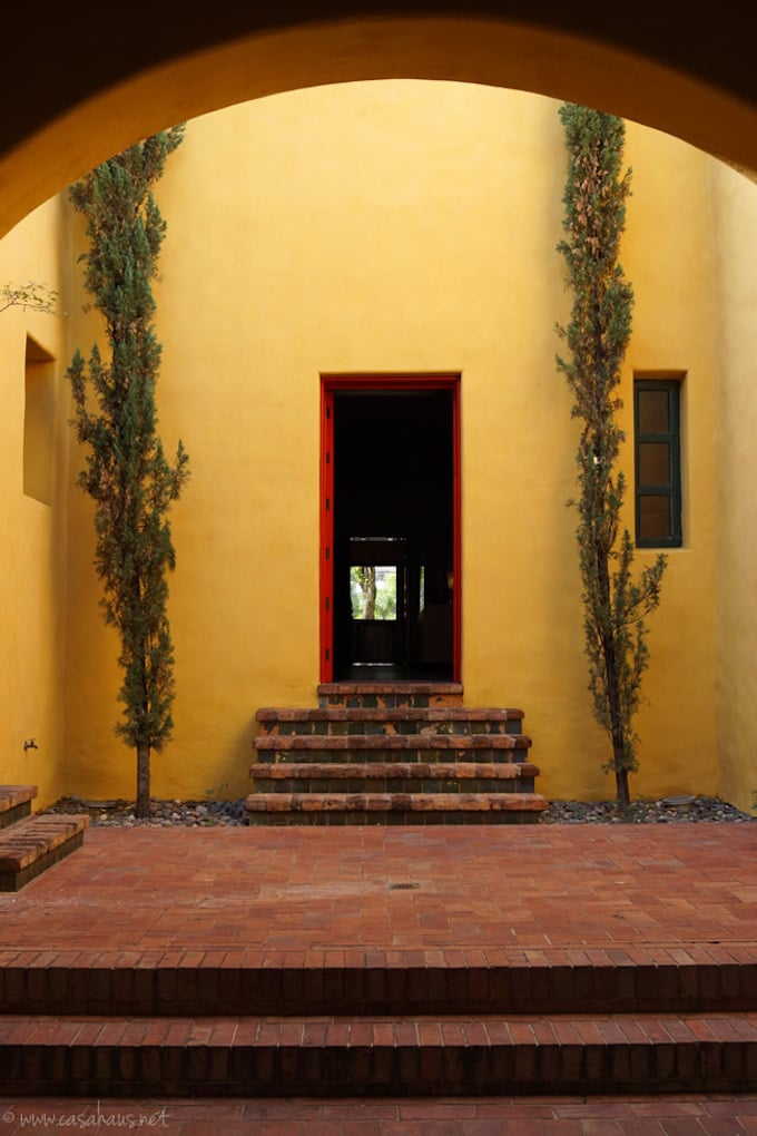maison exotique jaune arbres verts cour intérieure briques rouges